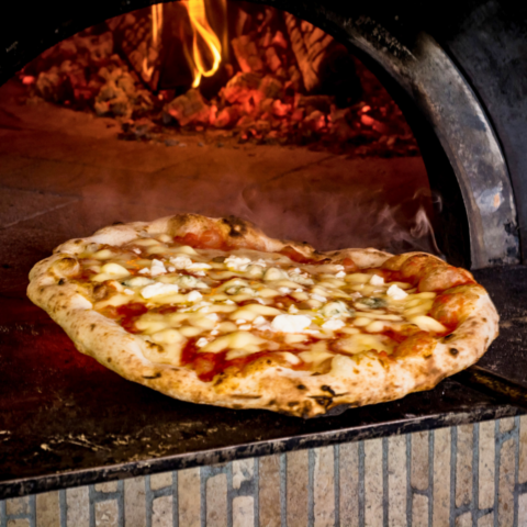 Cooked pizza being pulled out of wood oven from Solo Italia, a Canadian company