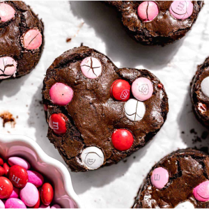 Recipe for chocolate fudge brownies cut into heart shapes with pink m&ms on top