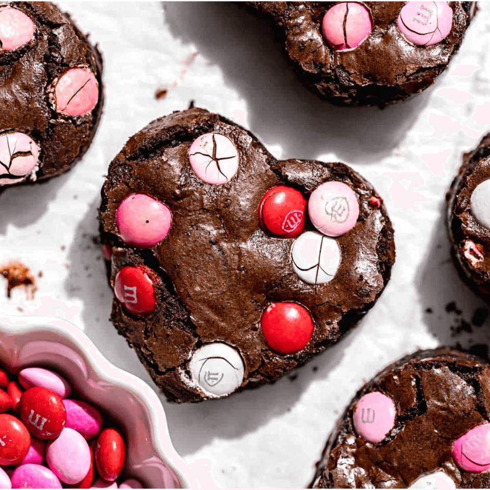 Recipe for chocolate fudge brownies cut into heart shapes with pink m&ms on top