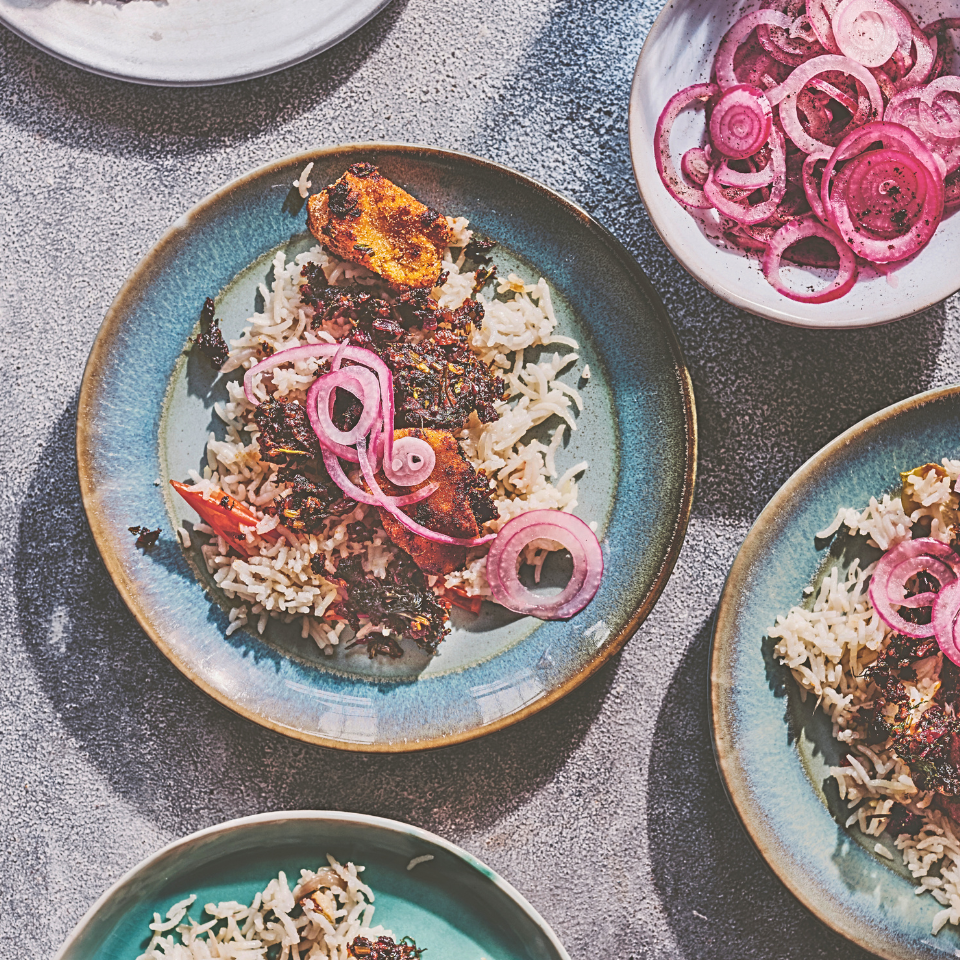Crispy tofu served on a bed of rice, topped with pickled red onion