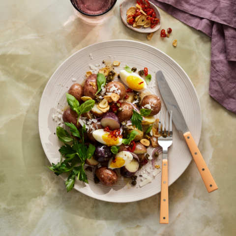 Red potato salad with fresh green herbs, jammy quartered eggs, sliced chili and toasted garlic.