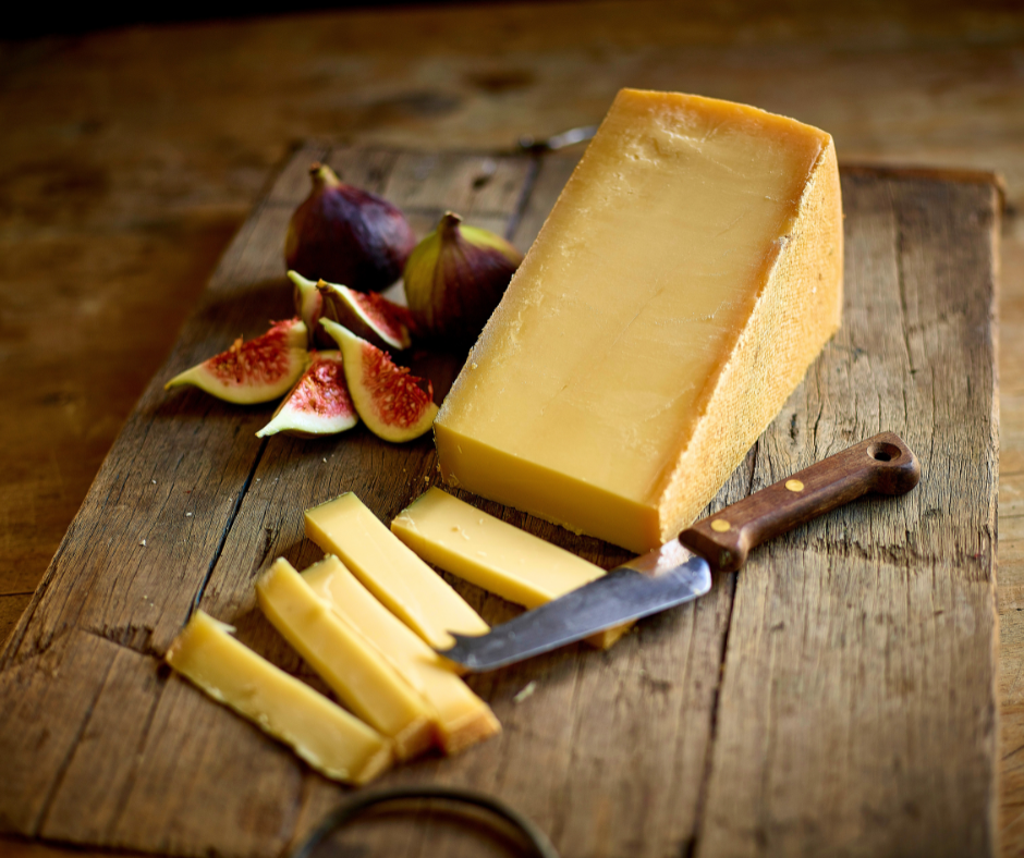 A wedge of authentic Austrian Vorarlberger Bergkäse on a cutting board served with figs