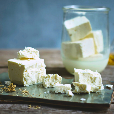 Authentic green feta in cubes and sitting in glass of brine