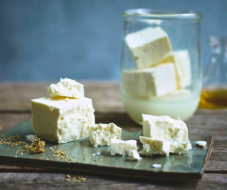 Authentic green feta in cubes and sitting in glass of brine