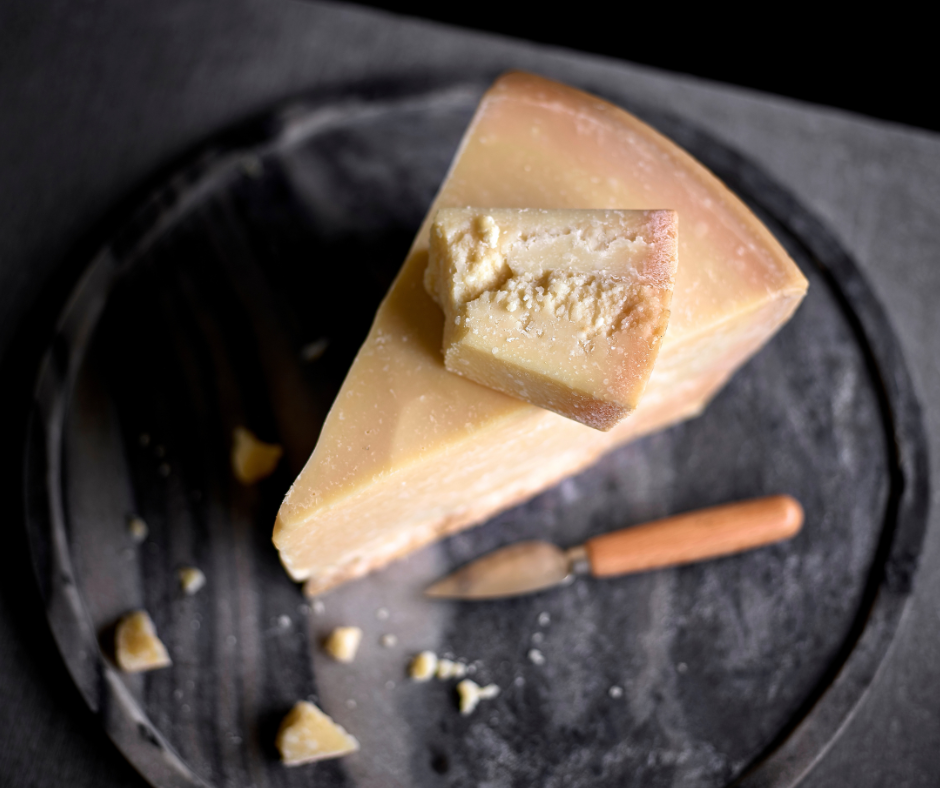 a wedge of Authentic Parmigiano Reggiano sitting on black slate plate