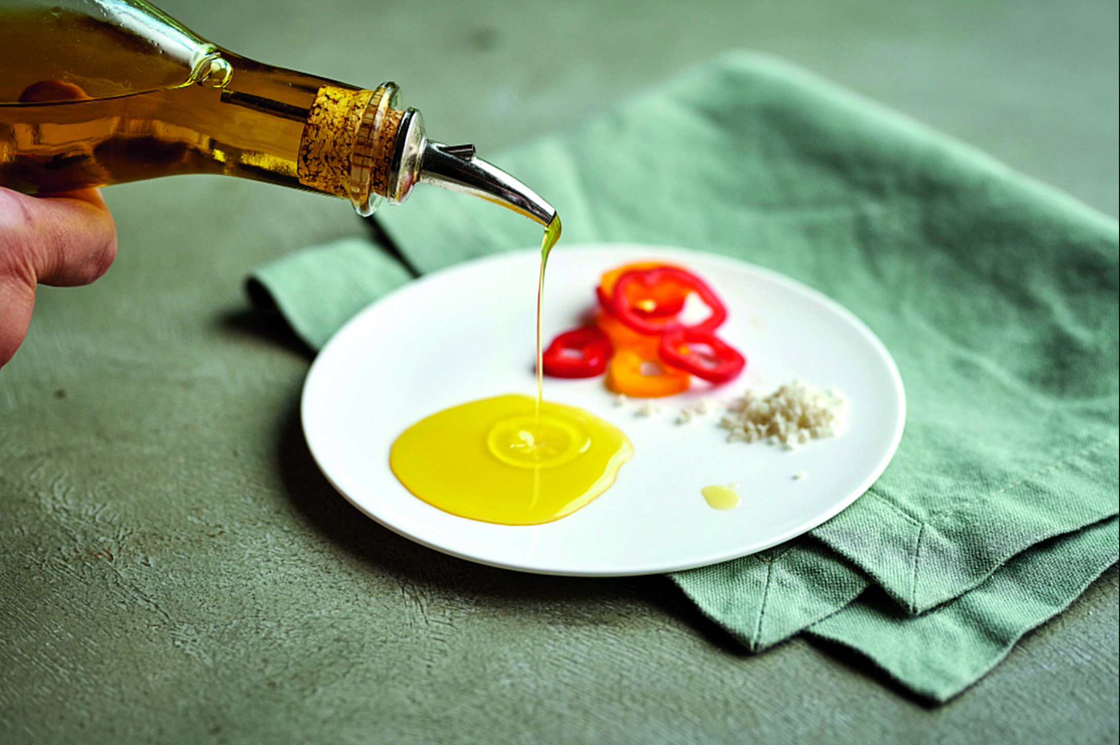 Priego de Córdoba Olive Oil is being poured onto a plate. It will be used to enjoy peppers and bread.