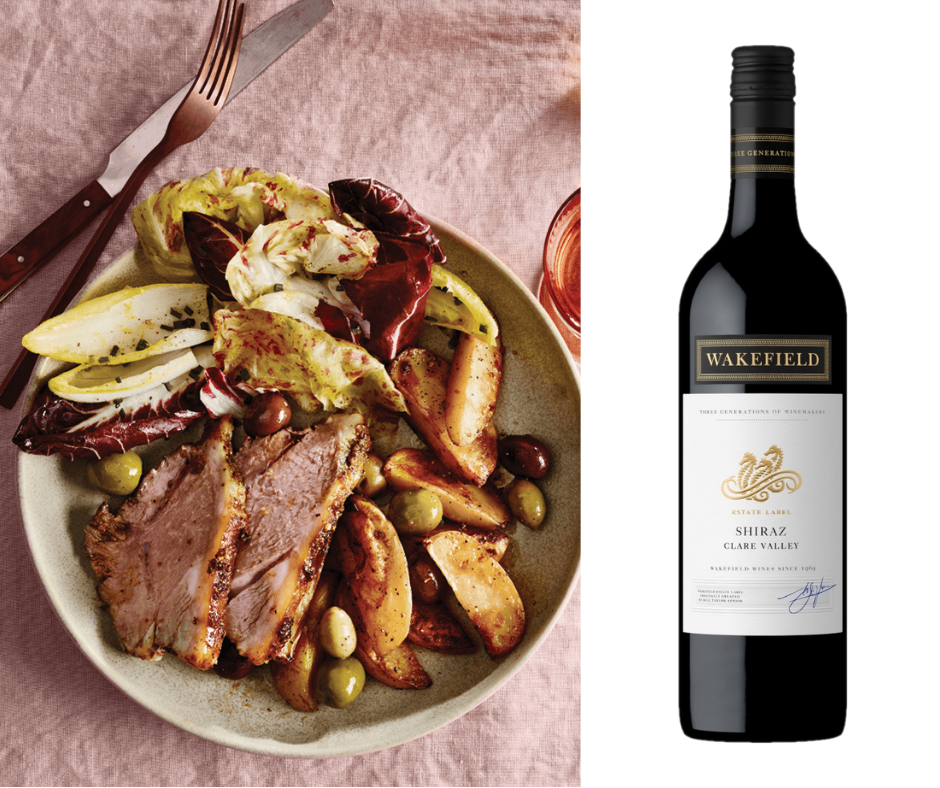 Roast lamb with potatoes and olives and a beautiful endive salad next to a bottle of shiraz
