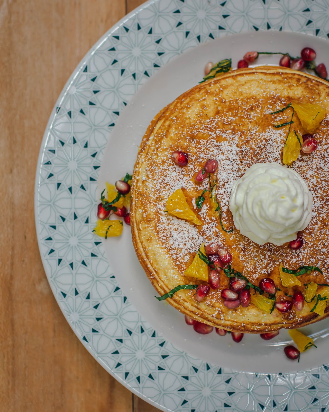 Pancakes topped with whipped cream and pomegranate pieces. 