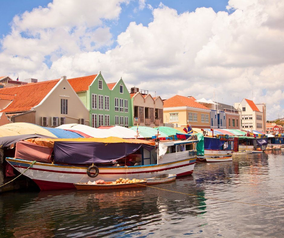 A Floating Market in, Curaçao with colourful old boats lined up against a row of colourful houses