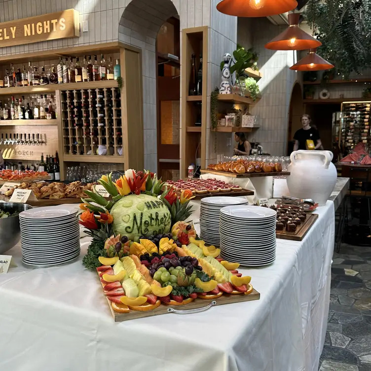 A fruit board on a white table with "Happy Mother's Day" carved onto the skin of a watermelon. 