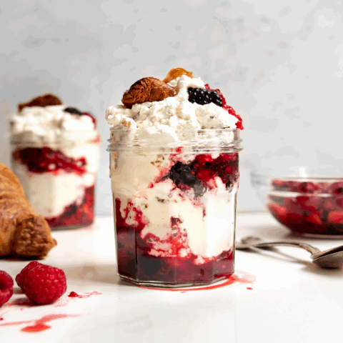 Jar filled with croissant, berries and whipped cream