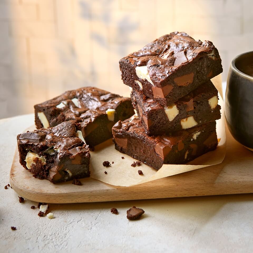 Five brownie squares on a wooden board.