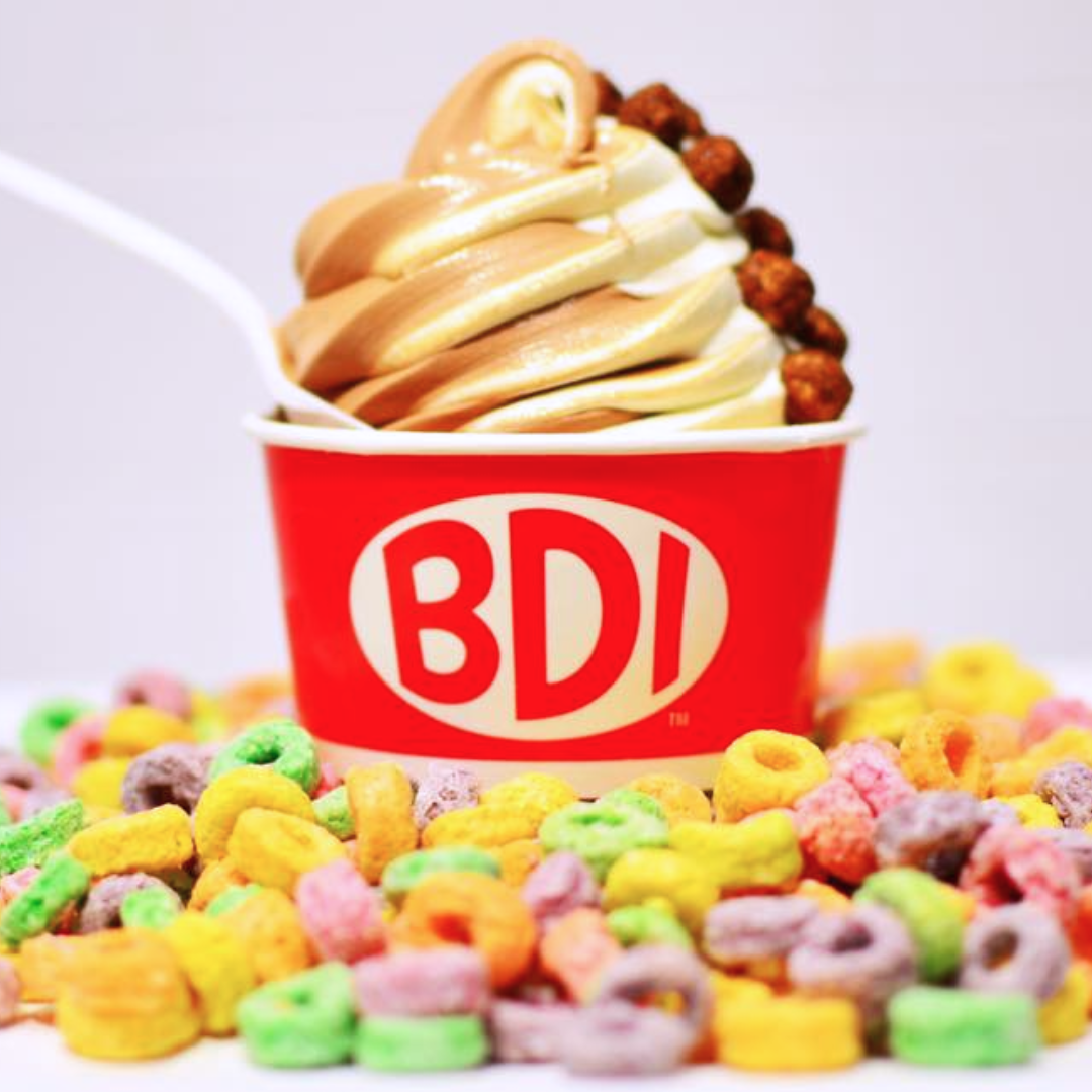 Brown and white cereal milk flavoured soft serve in a red cup with "BDI" logo on it.