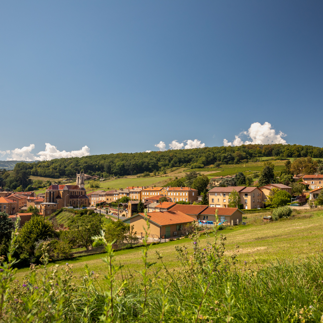 A small town in a green, hilly area with blue skies above.