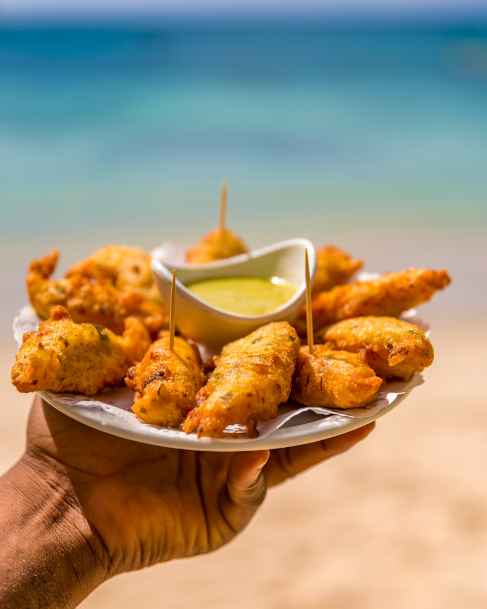 Holding fried accra against the backdrop of the turquoise caribbean sea