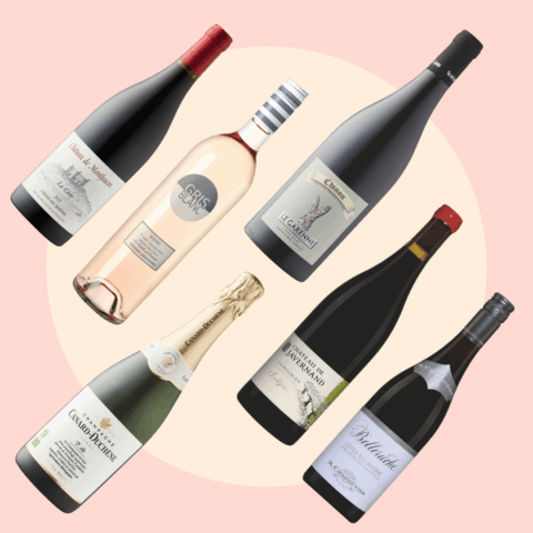 Six bottles of organic French wine in front of a cream and pink background.
