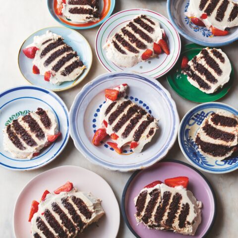 Slices of chocolate ripple cake with strawberries on colourful plates.