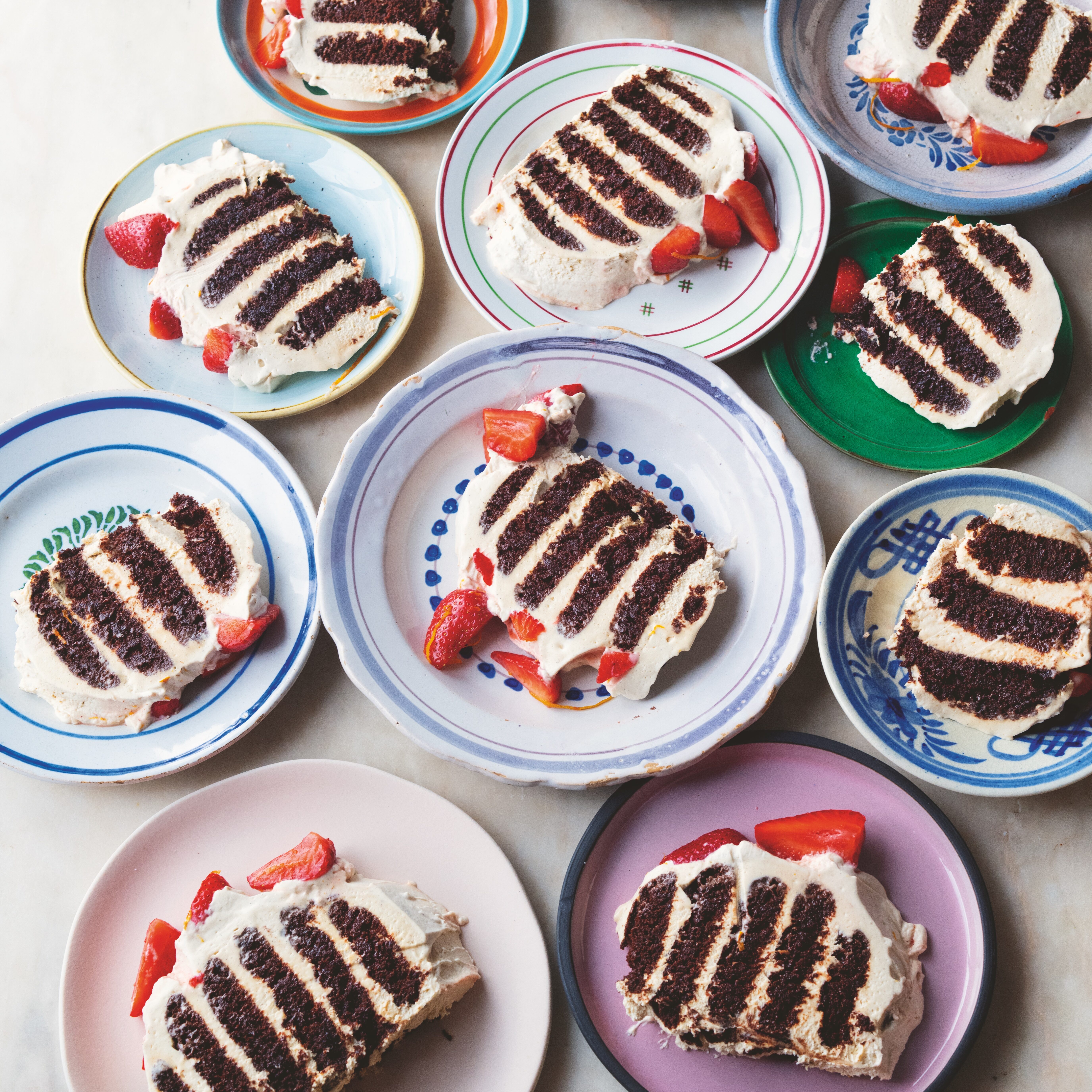 Slices of chocolate ripple cake with strawberries on colourful plates.