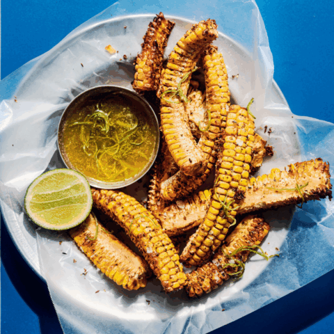Plate of corn ribs with half a lime and a side of zesty butter.