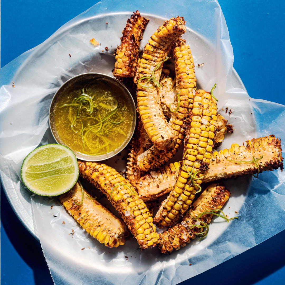 Plate of corn ribs with half a lime and a side of zesty butter.