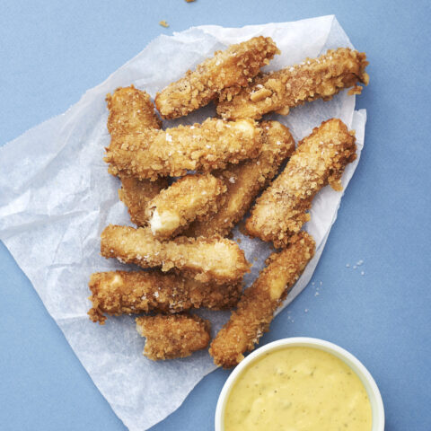 Halloumi fries on top of wax paper with a side of béarnaise dip.