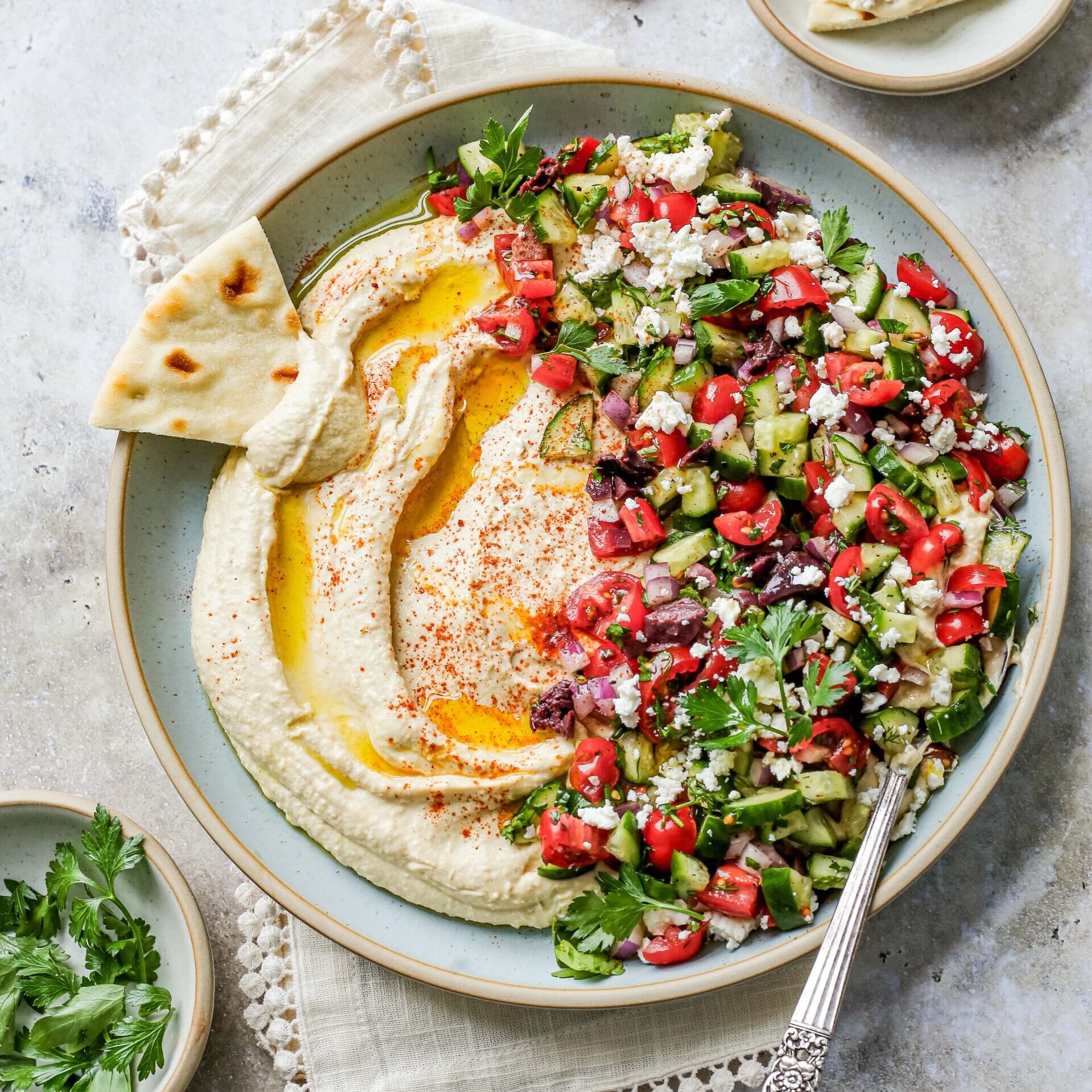 A bowl of Mediterranean hummus salad with a slice of pita bread.