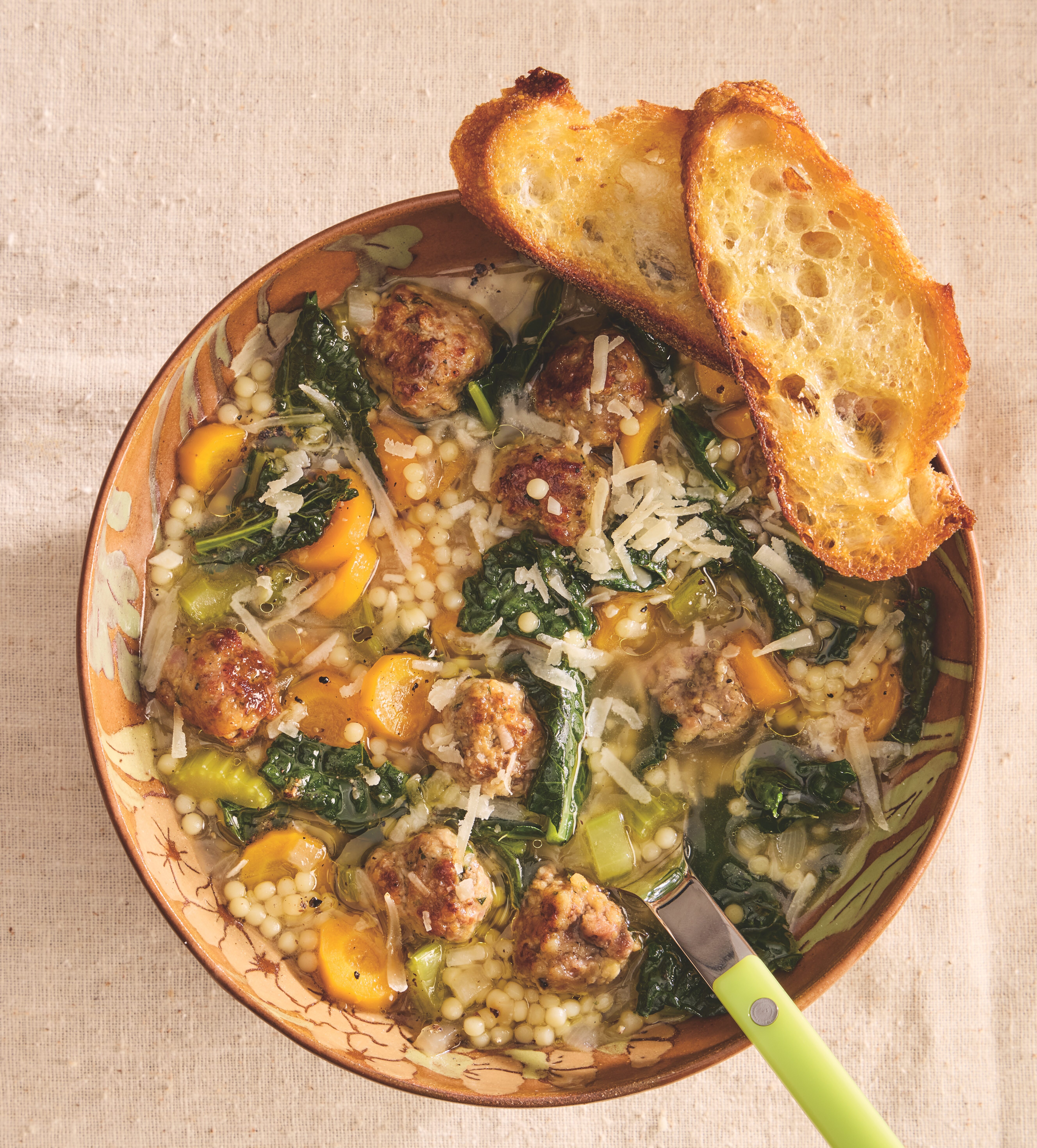 Bowl of Italian Wedding Soup with tender meatballs, fresh greens, and broth, served with a spoon