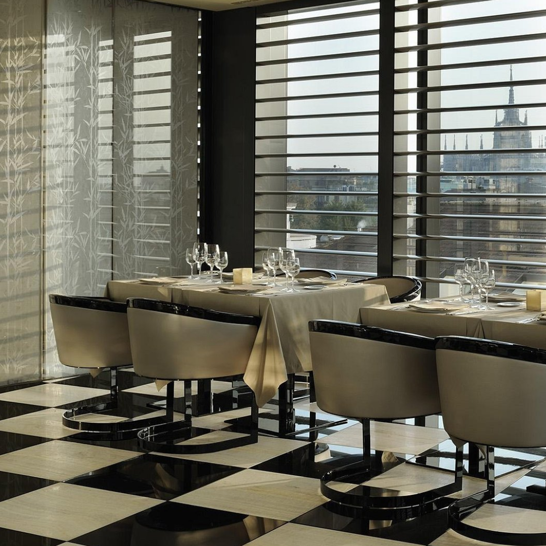 The interior of a restaurant facing a window, with two tables and a checkered floor.