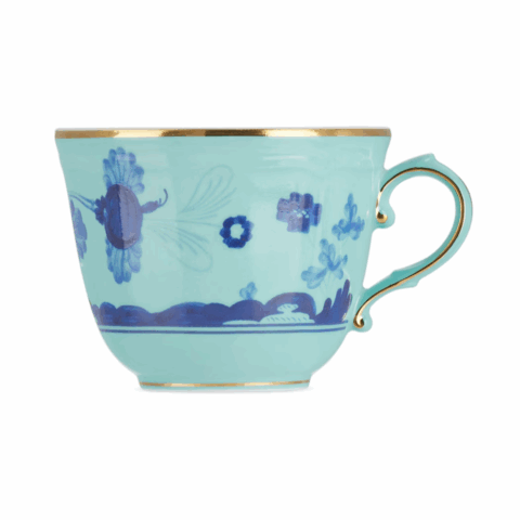 A light blue porcelain espresso cup with gold trim and a natural scene painted on it.