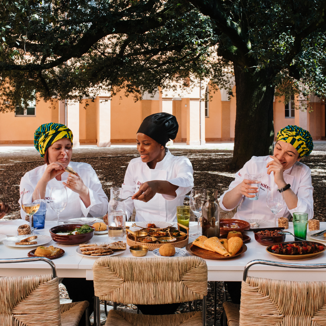 Three women smiling and eating outdoors.