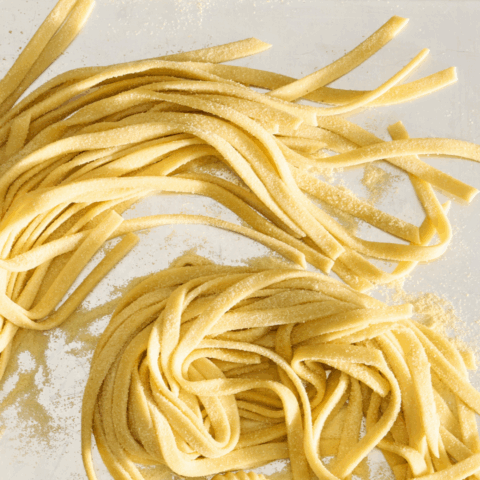 Uncooked pasta noodles on a reflective surface.