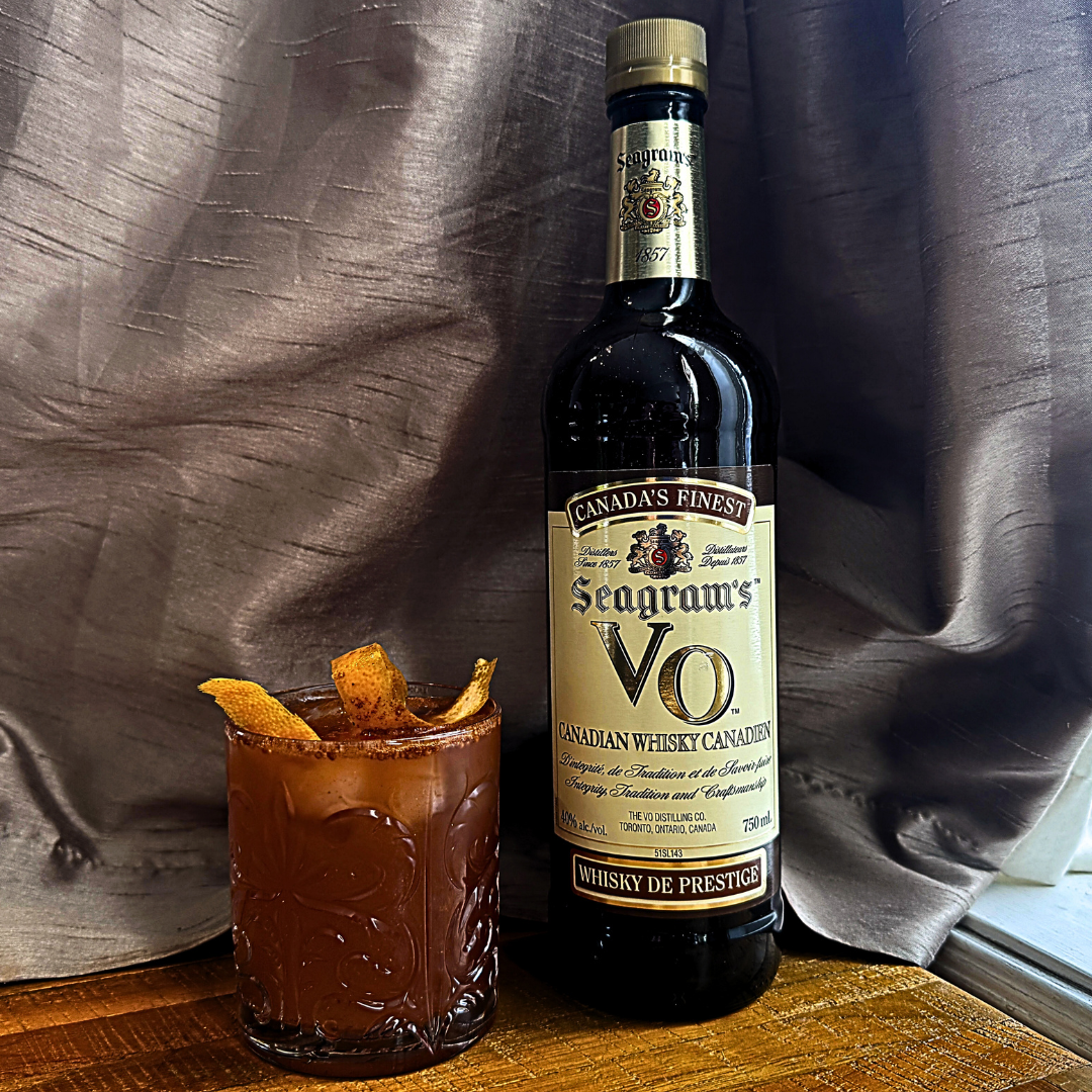A cocktail glass next to a bottle of whisky. 