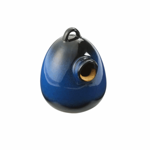 A dark blue oval-shaped ceramic bird home with a small circular opening.