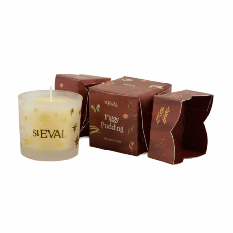 Brown Christmas cracker next to a yellow candle in a glass vessel.