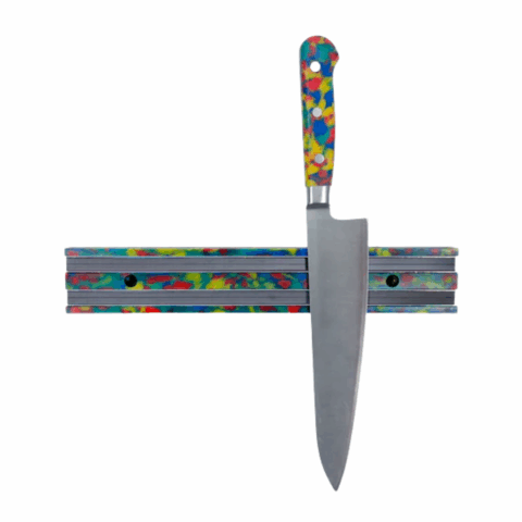 A knife with a swirled rainbow plastic handle on a rainbow knife magnet.