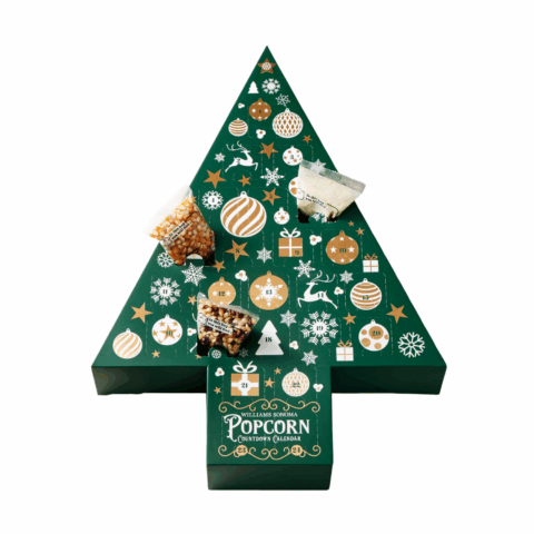 A green tree-shaped advent calendar with small bags of popcorn kernels coming out of three compartments.