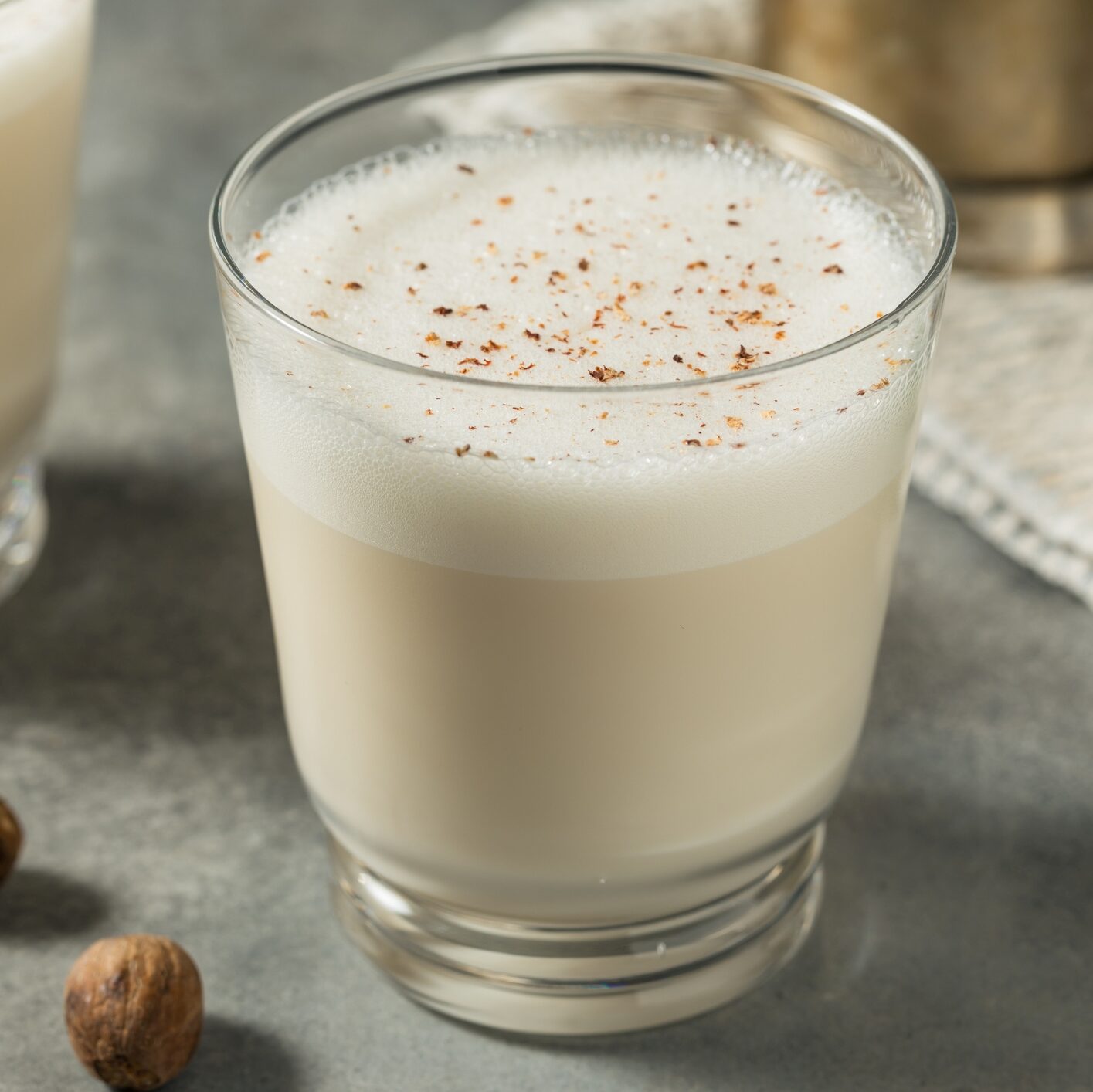 A glass filled with eggnog and topped with nutmeg.