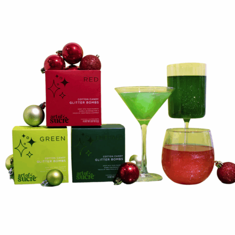 Three boxes of glitter bombs and three glasses of sparkling cocktails with tiny ornaments around them.