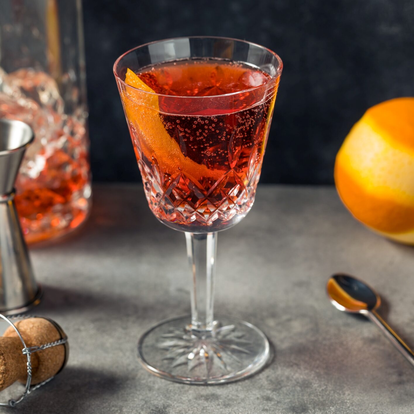A negroni spagliato with an orange twist in a glass on a gray countertop. 