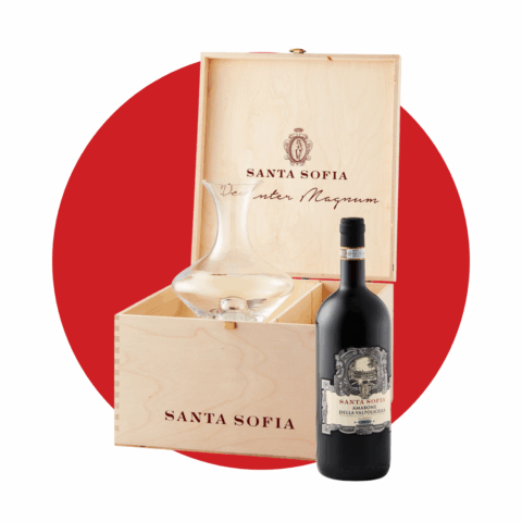 A black bottle of wine next to a wooden box holding a clear glass decanter.