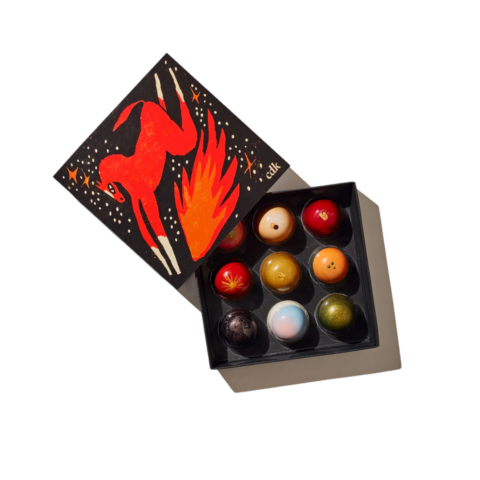 A black box with the design of a red horse jumping over flames opened to show nine chocolate truffles.
