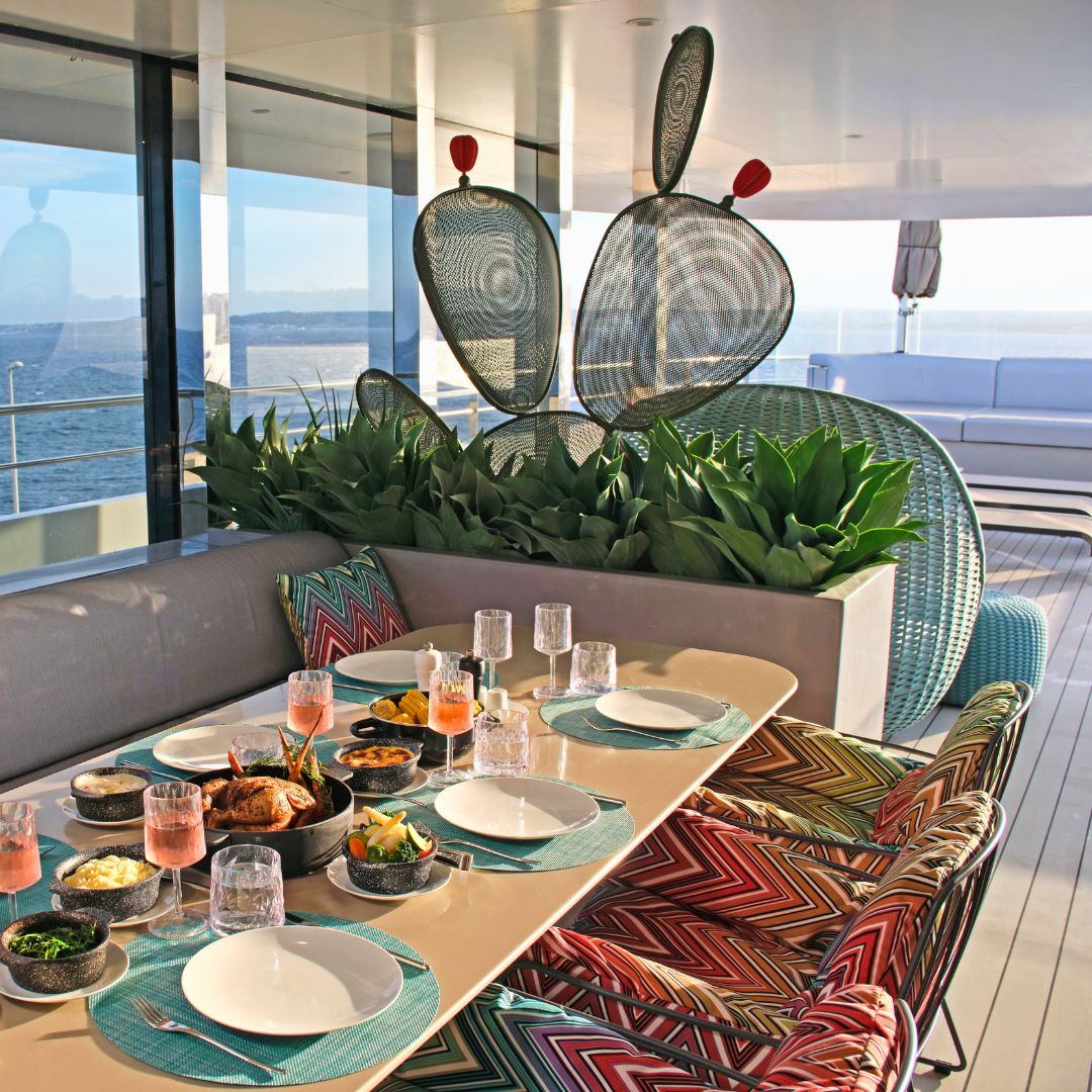 Outdoor dining area aboard an Emerald Yacht with a table set for a gourmet meal overlooking the ocean.