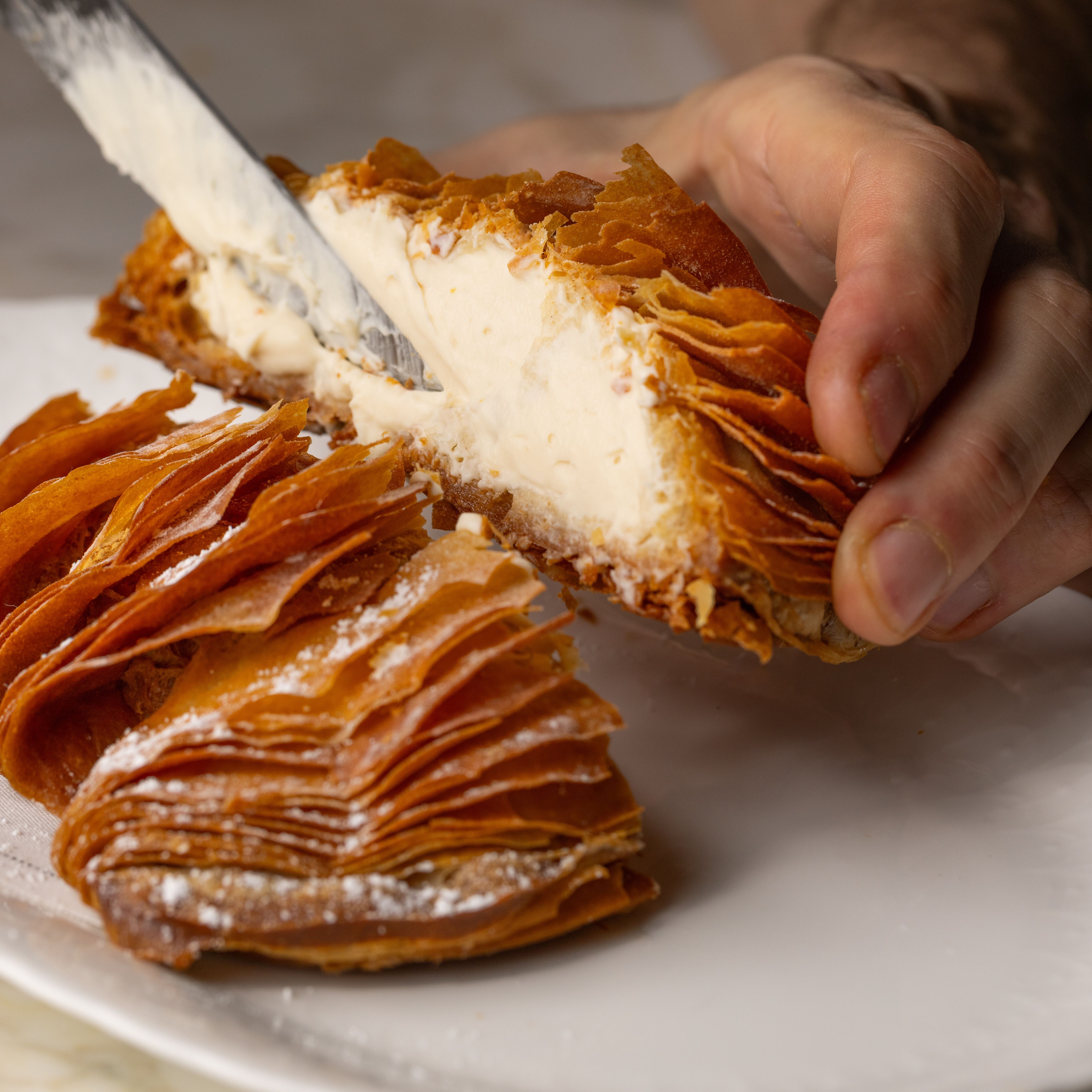 A hand holding up half of a sfogliatella showing the cream inside.