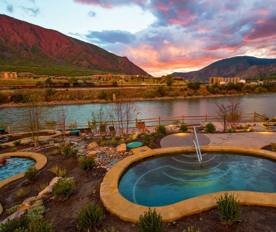 Hot springs pools overlooking a river and mountains at sunset in Glenwood Springs.