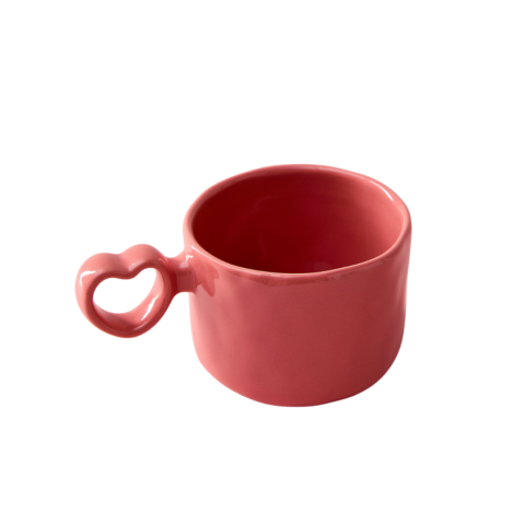 A pink ceramic mug with a heart-shaped handle.