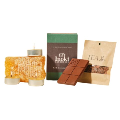 Three candles on a bar of beeswax, a chocolate bar, a bag of loose leaf tea and a green box.