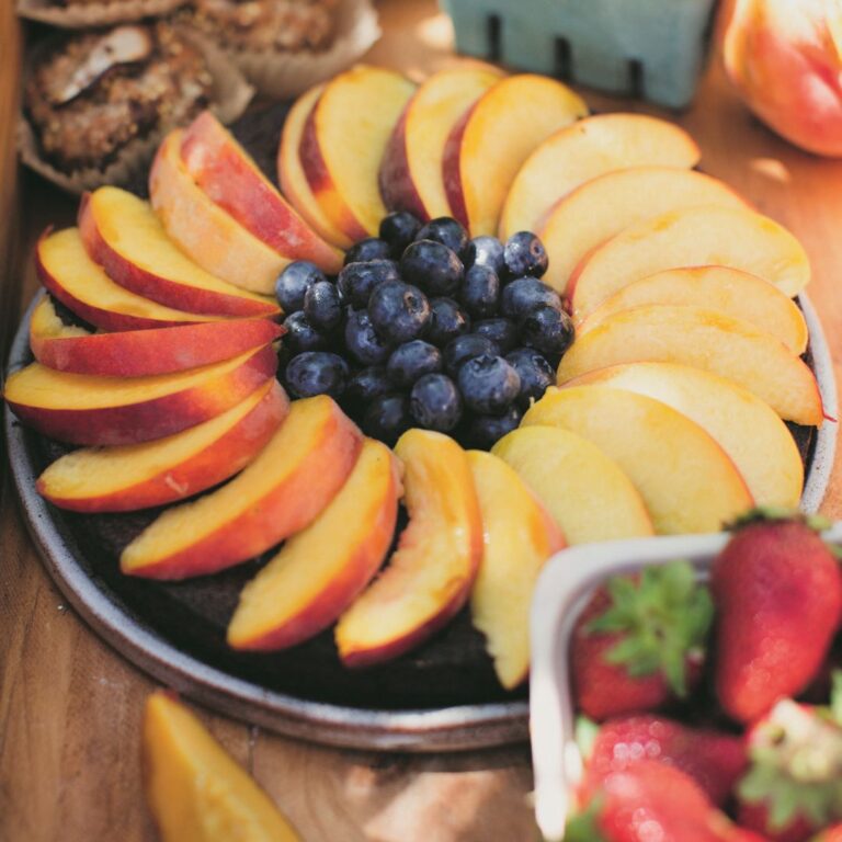 Naturally-gluten free citrus olive oil cake covered with fresh peaches and blueberries