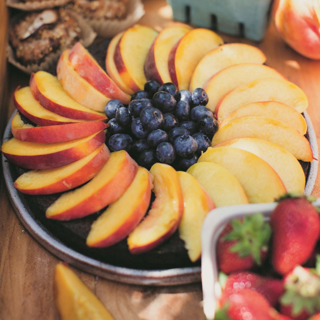 Naturally-gluten free citrus olive oil cake covered with fresh peaches and blueberries