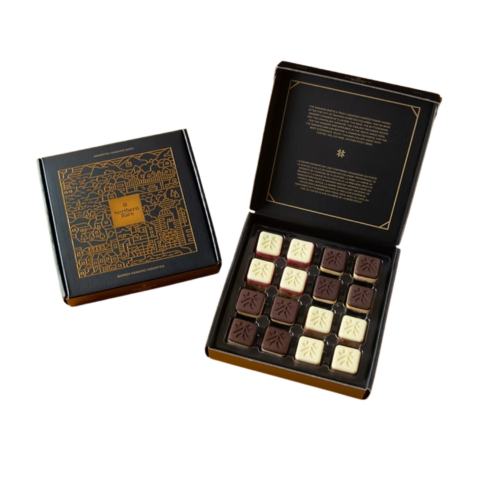 A closed black box next to an opened black box with 16 mini Nanaimo bars.