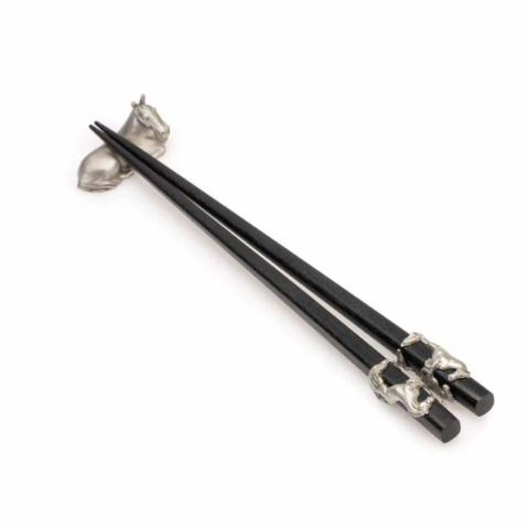 A black pair of wooden chopsticks with pewter horse details and a pewter horse chopstick rest.